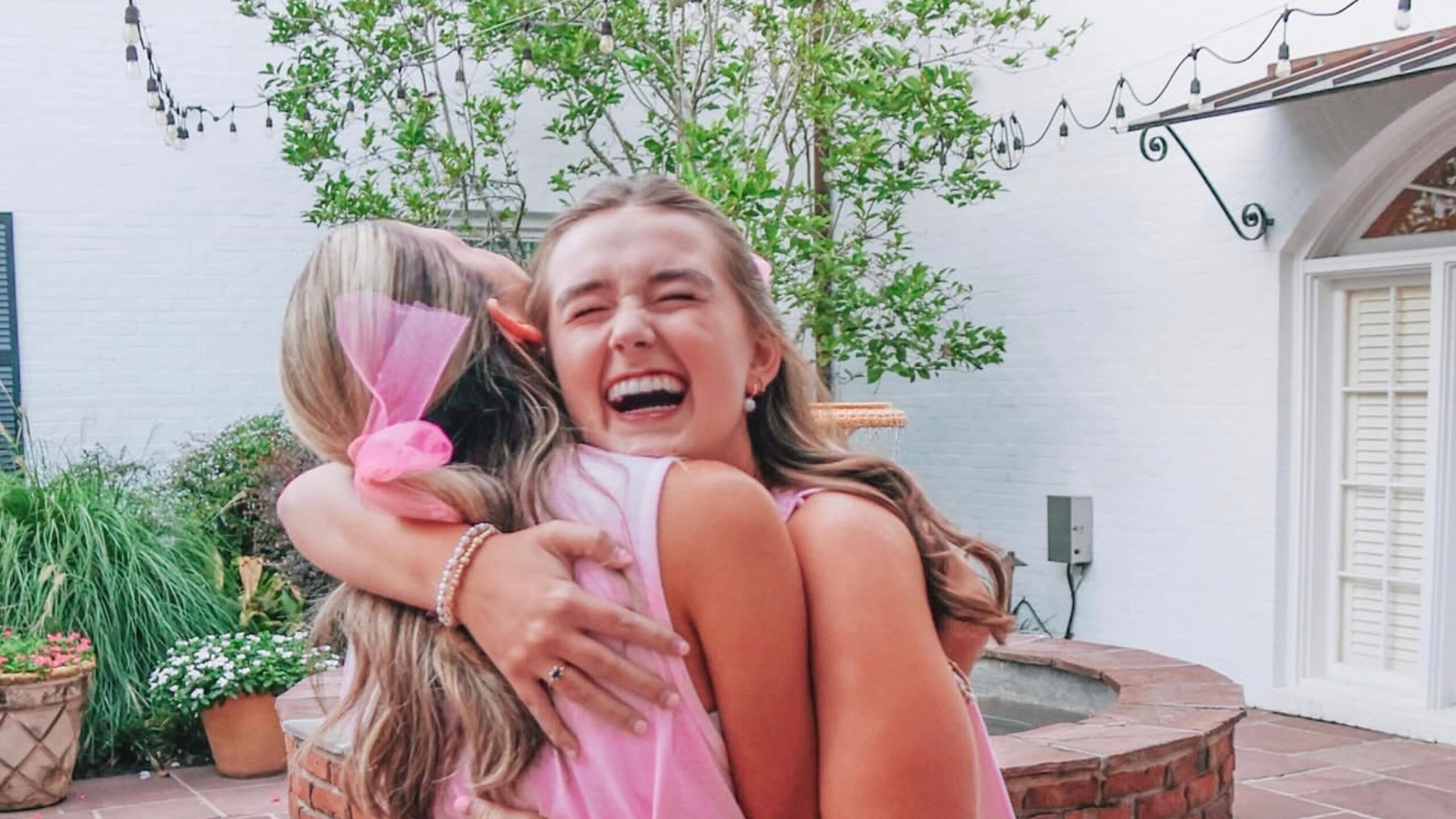 two sisters hugging outside in a courtyard laughing and smiling