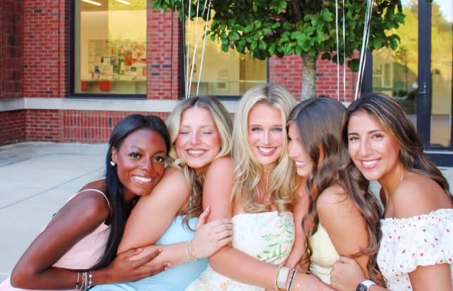 5 sisters holding each other posising for a photo sitting down