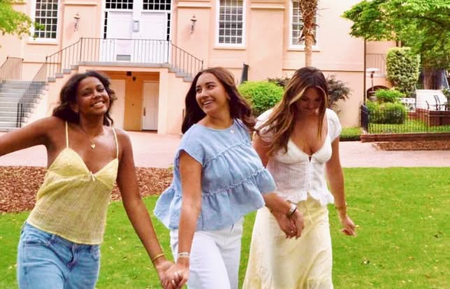 sisters holding hands looking at one another walking