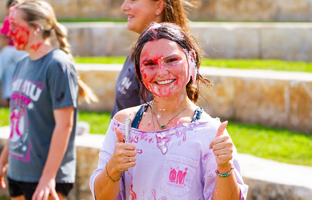 PMu smiling for a photo with paint on their face smiling with thumbs up