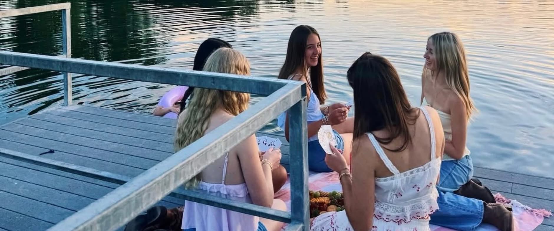 Sisters sitting on the board walk next to a lake
